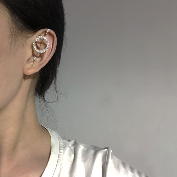 Close-up of an ear wearing a silver hoop earring with a gray background