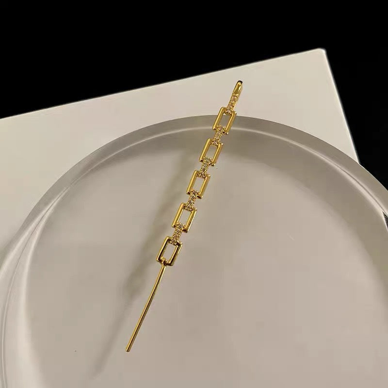 Gold chain earring on a white surface with a black background