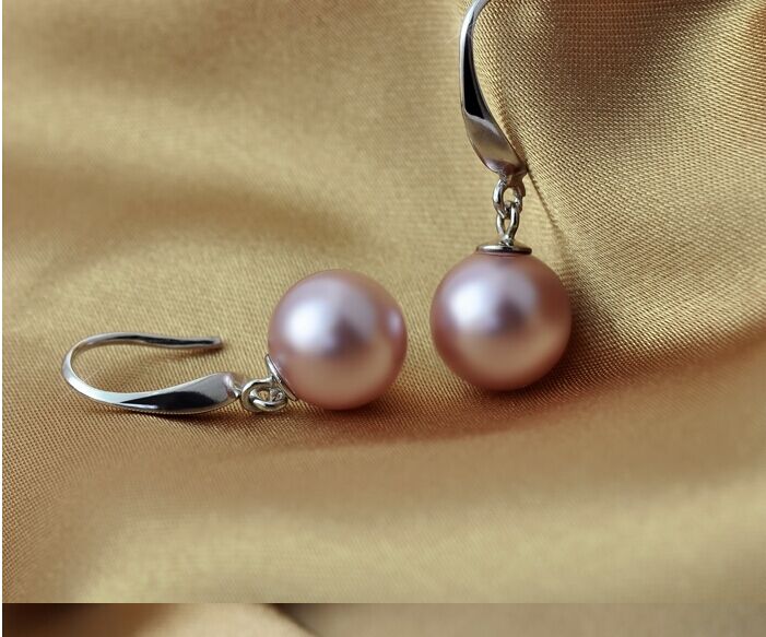Pair of pink pearl earrings on a beige fabric background