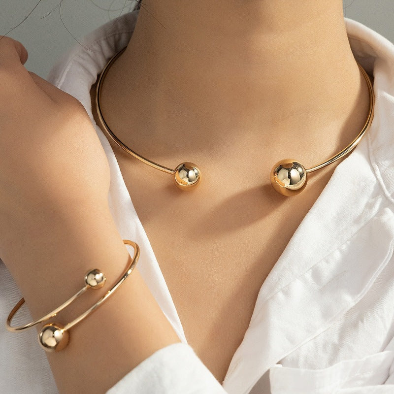 Gold necklace and bracelet set on a person wearing a white shirt.