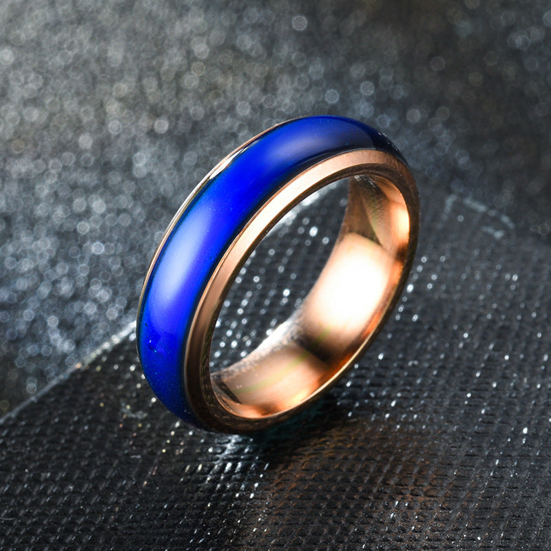 Ring with blue and rose gold band on a textured black background