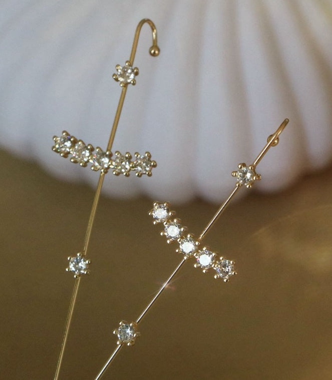 Gold earrings with diamond-like stones on a neutral background