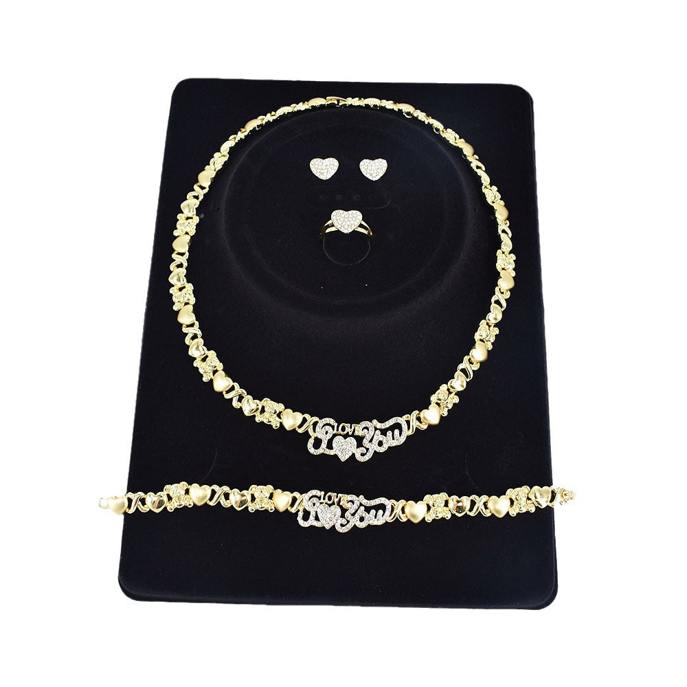 Gold necklace and bracelet set on a black display stand with heart-shaped earrings.