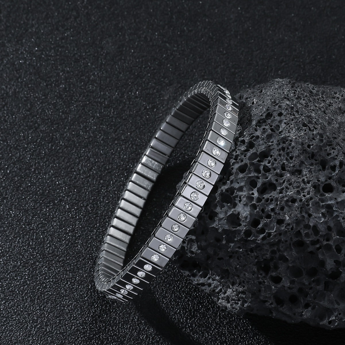 Metallic bracelet with embedded stones on a textured black surface