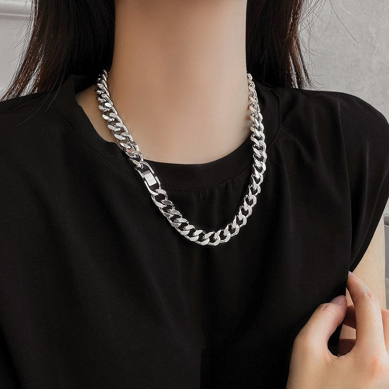 Person wearing a silver chain necklace with a plain background