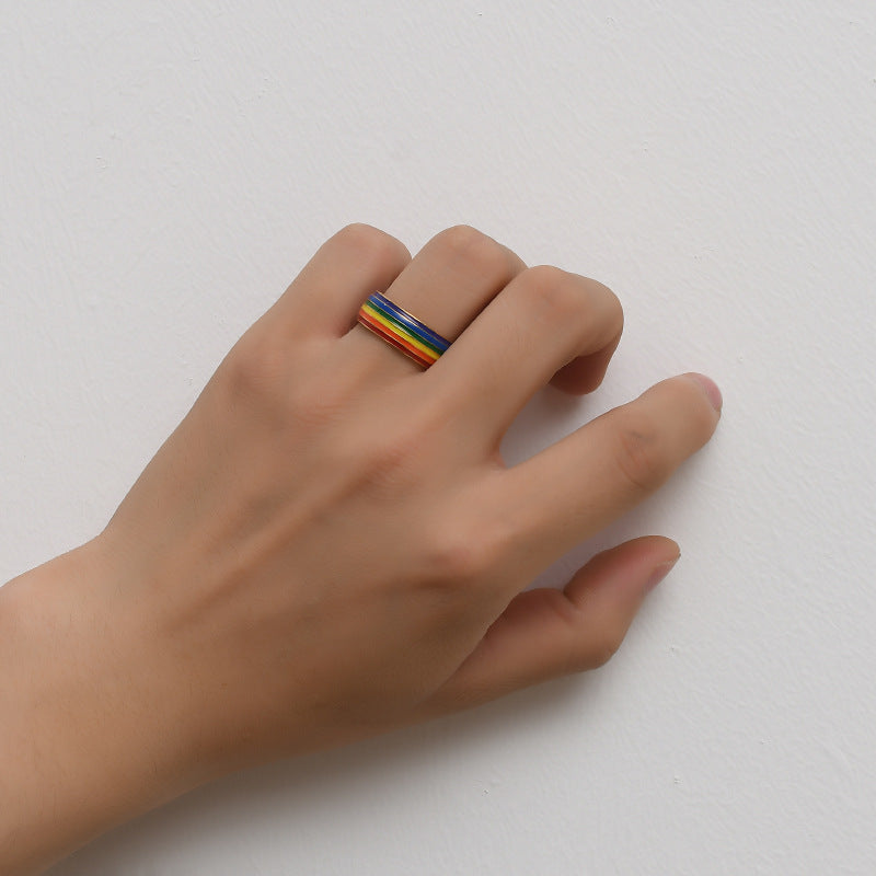 Hand wearing a rainbow ring on a light gray background