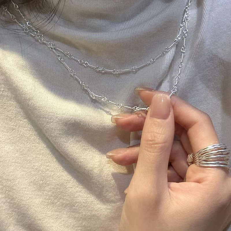 Close-up of a hand wearing multiple silver rings with a light background