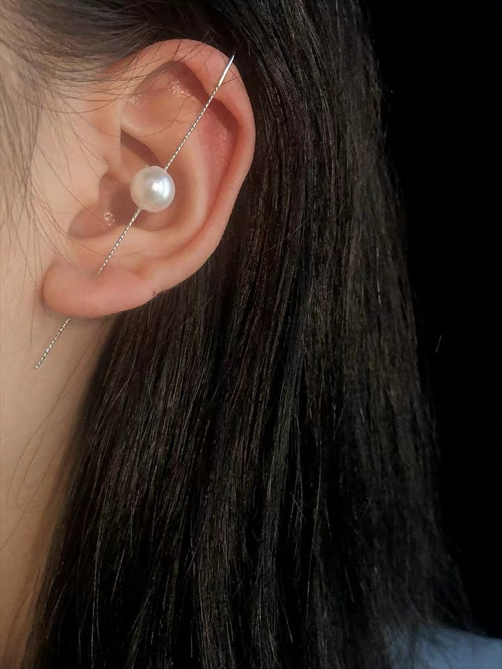 Close-up of an ear wearing a pearl earring with dark hair and blurred background