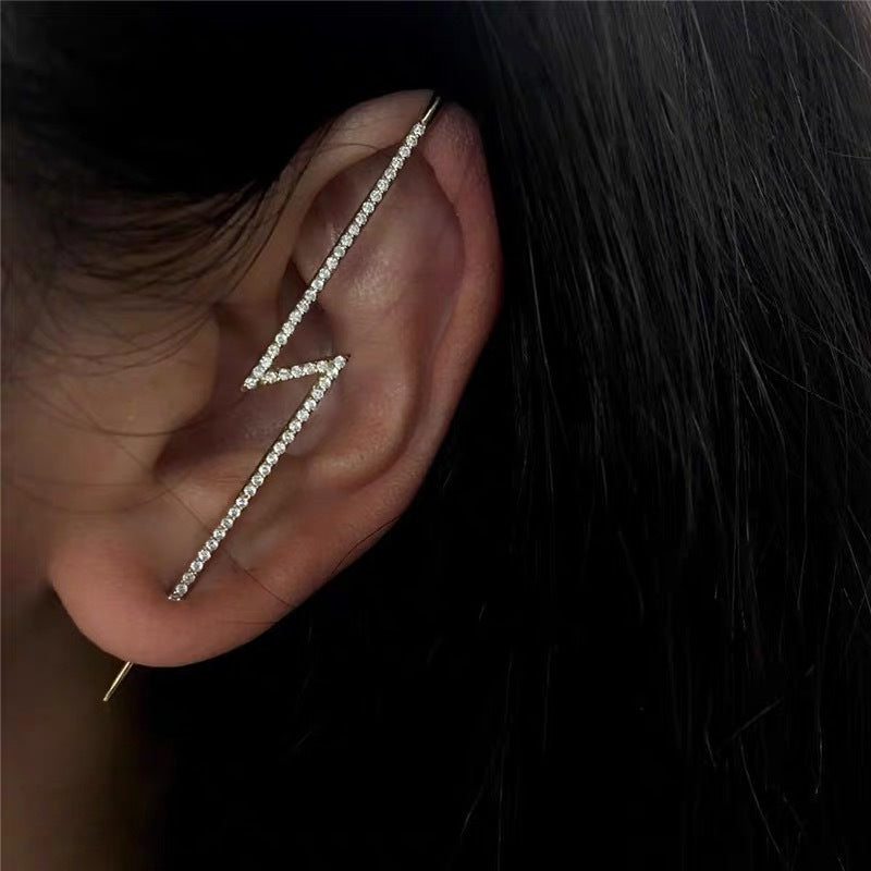 Close-up of an ear wearing a delicate diamond earring with a dark background
