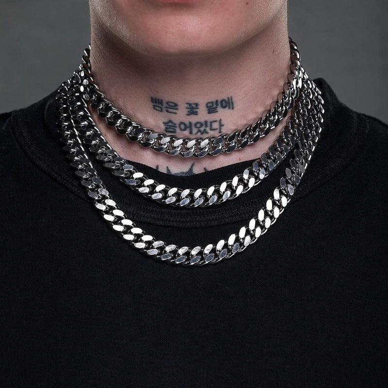 Person wearing multiple silver chain necklaces on a dark background