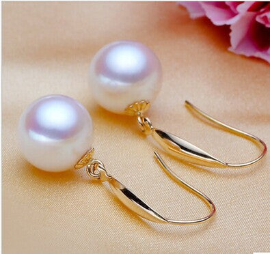 Pearl earrings with gold hooks on a soft background