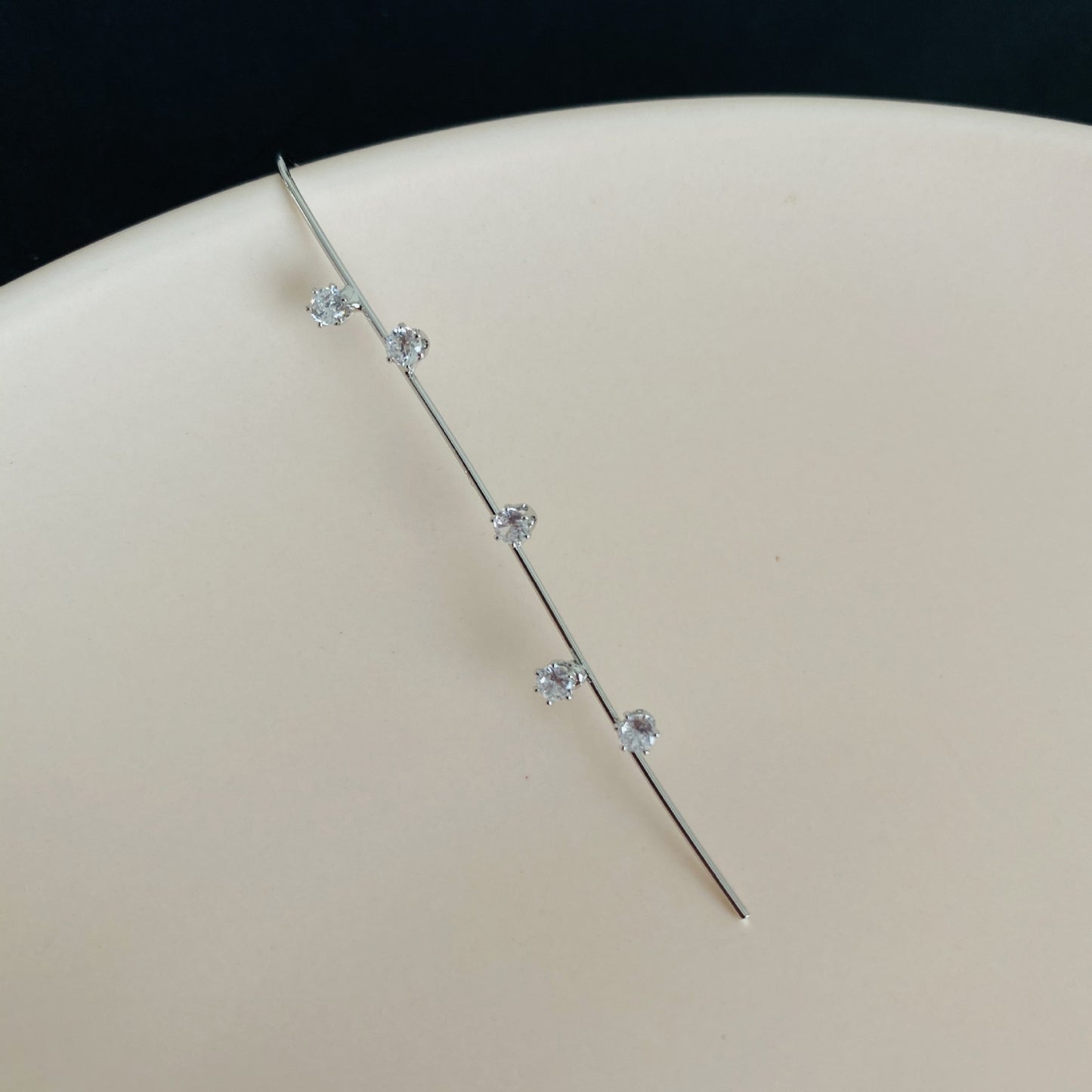 Silver hairpin with small crystals on a beige surface