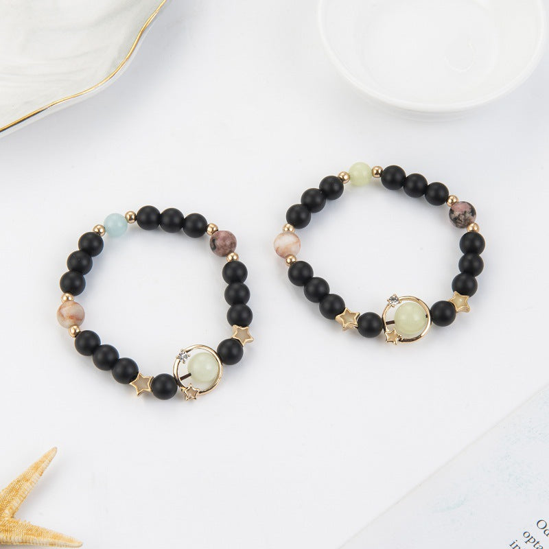 Two black beaded bracelets with gold accents on a white surface.