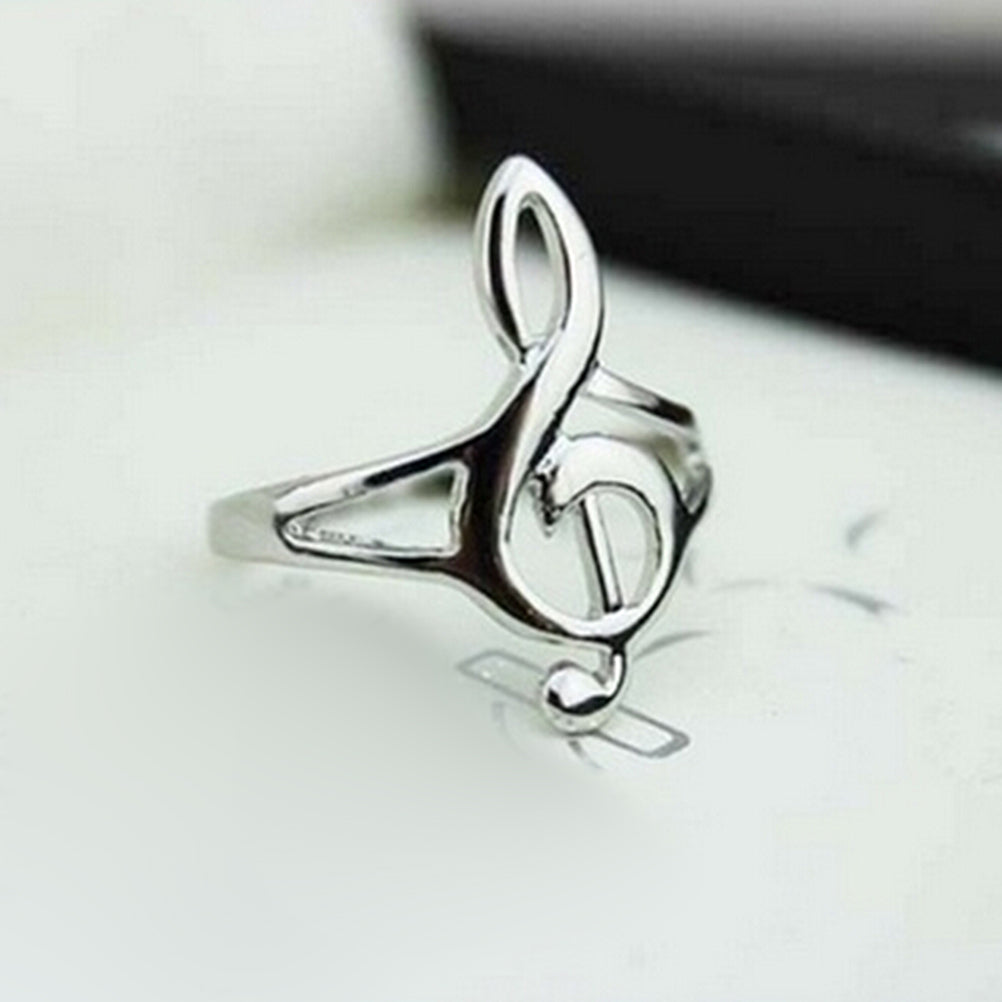 Silver ring with a music note design on a white surface