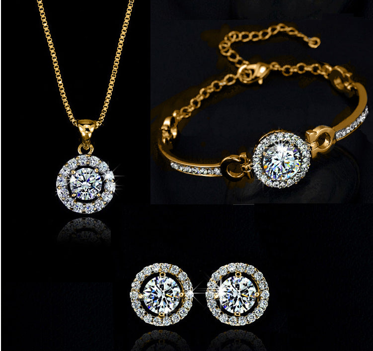 Gold jewelry set with necklace, bracelet, and earrings on a black background