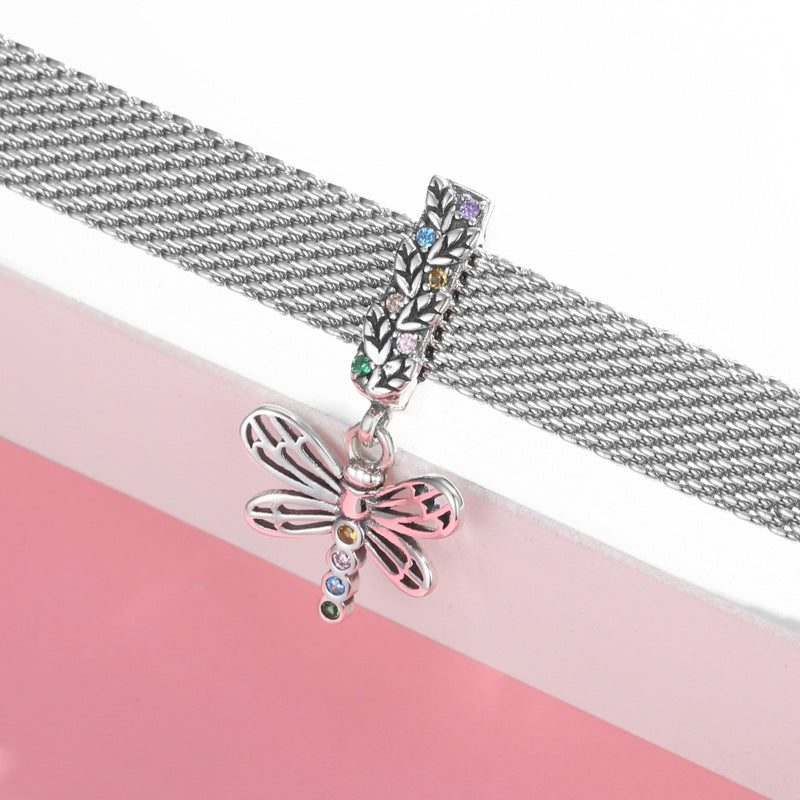 Silver chain necklace with a dragonfly pendant on a pink and white background