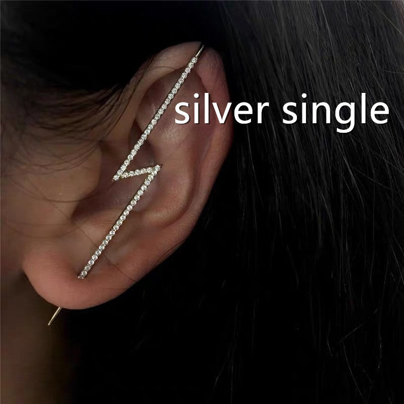 Silver single ear cuff worn on an ear with dark hair background