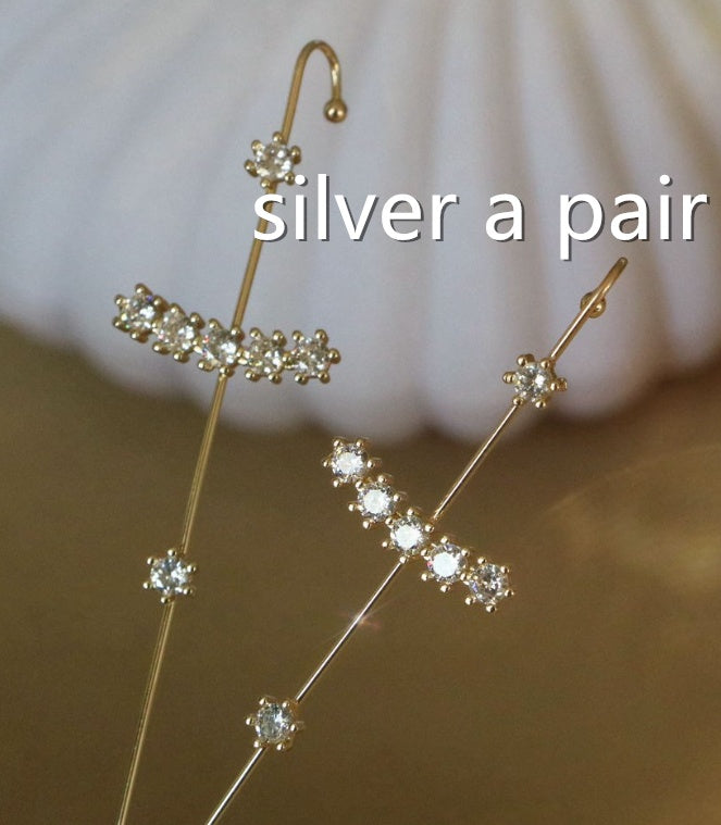 Gold earrings with clear stones on a blurred background