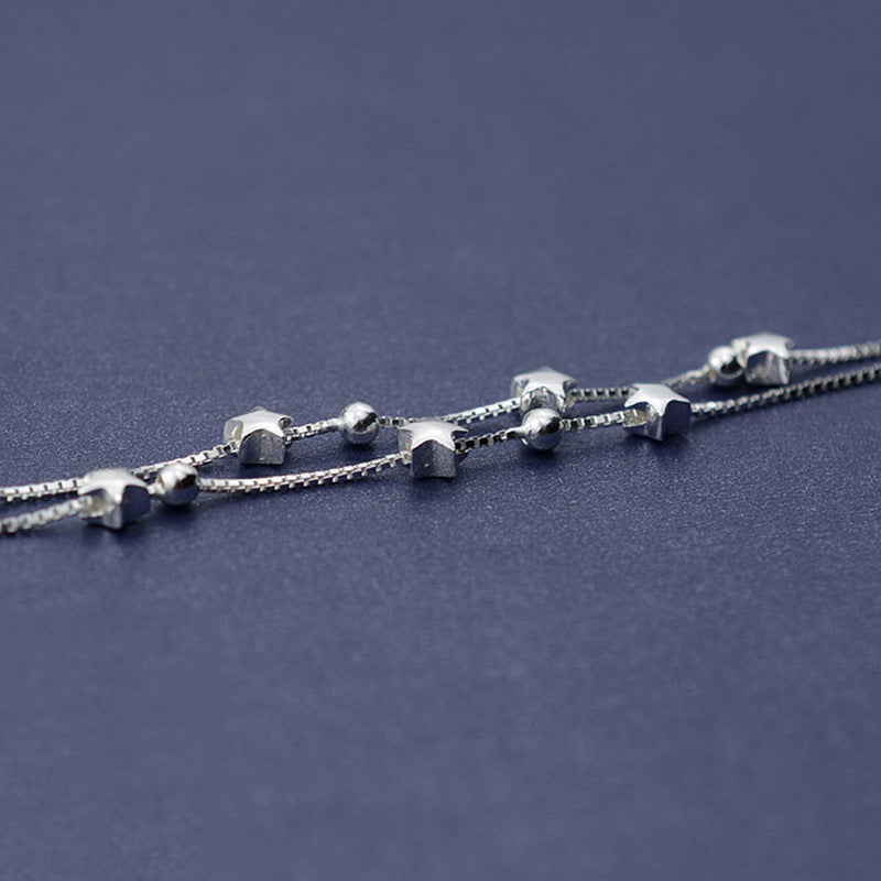 Silver bracelet with star-shaped beads on a dark blue background