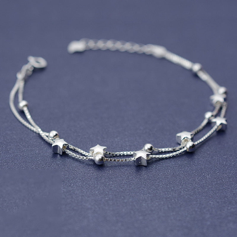Silver bracelet with star and bead details on a dark blue background