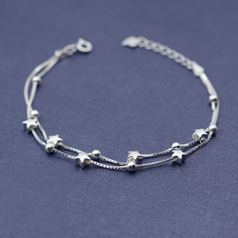 Silver bracelet with star-shaped charms on a dark blue background