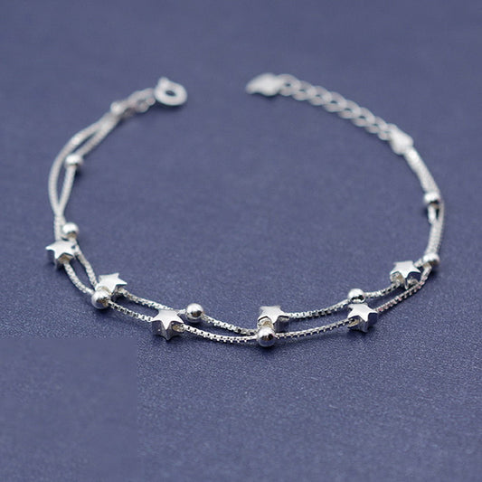 Silver bracelet with star-shaped charms on a dark blue background