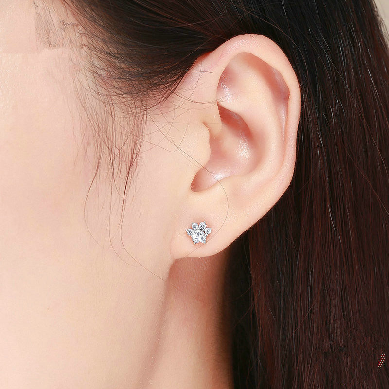 Close-up of an ear wearing a diamond stud earring with a blurred background