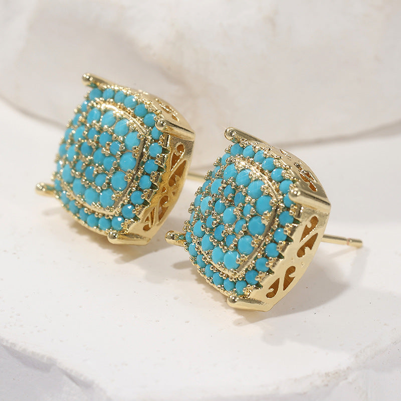 Gold earrings with turquoise stones on a white background