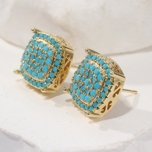 Gold earrings with turquoise stones on a white background