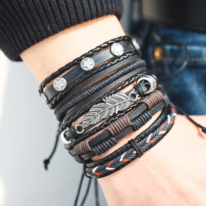 Multiple leather bracelets with metal accents on a wrist against a neutral background