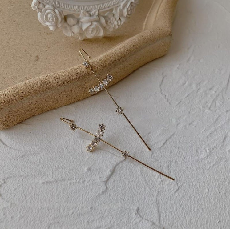 Pair of gold earrings with small stones on a textured surface