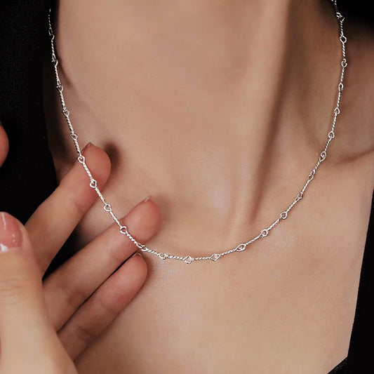 Silver necklace being worn on a person's neck with a blurred background