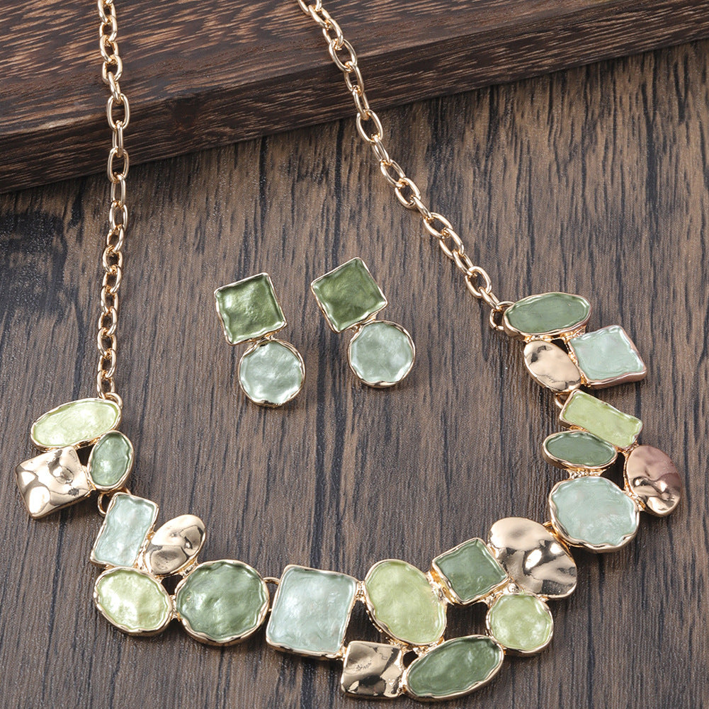 Necklace and earrings with green gemstones on a wooden surface