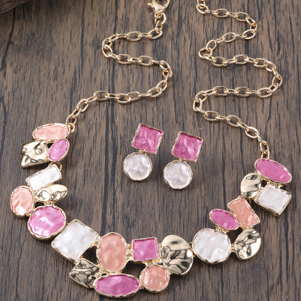 Necklace and earrings with pink and white stones on a wooden surface