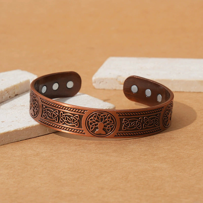 Copper bracelet with intricate designs on a wooden surface