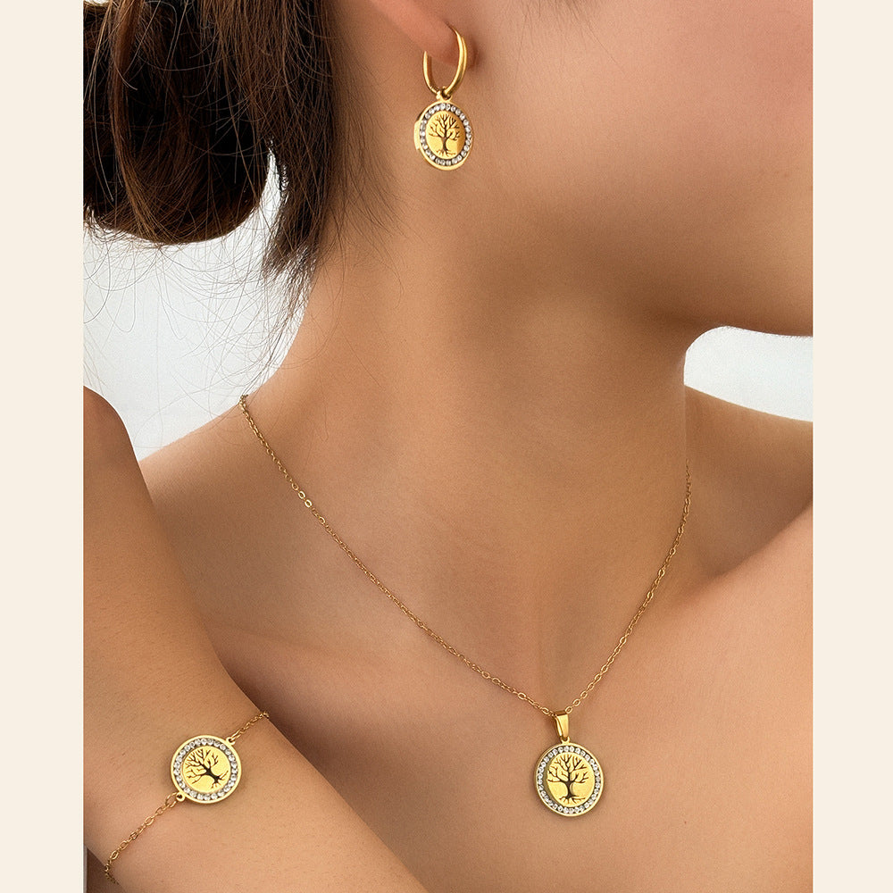 Gold necklace, bracelet, and earrings with tree-of-life design on a model.