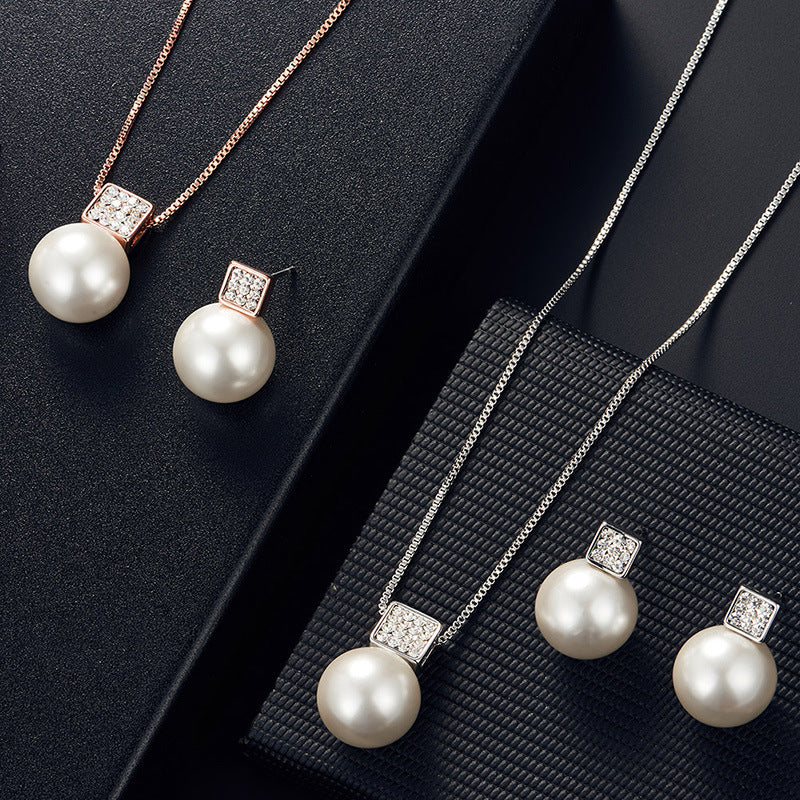 Pearl necklace and earrings set on a black textured surface
