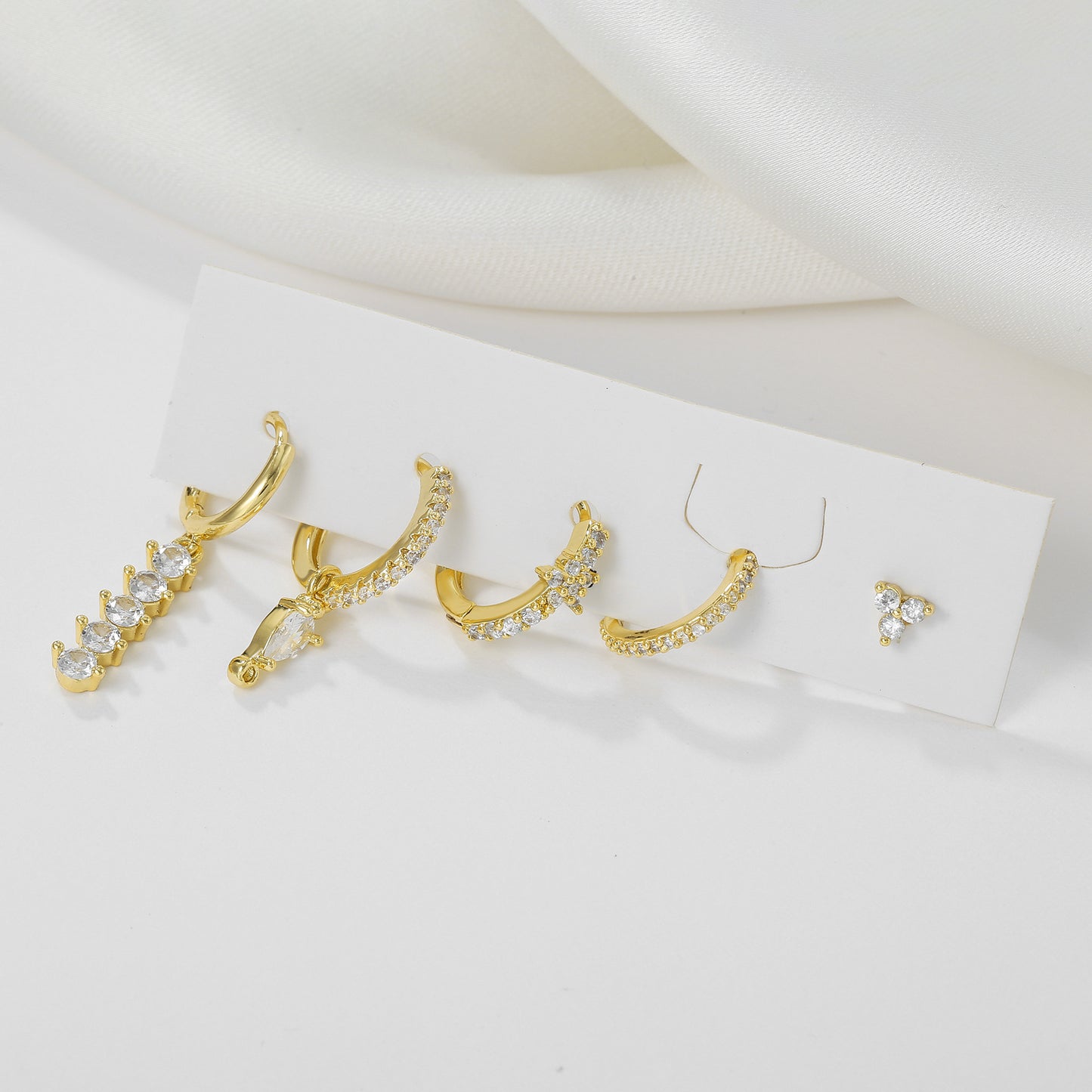 Gold earrings with clear stones on a white background