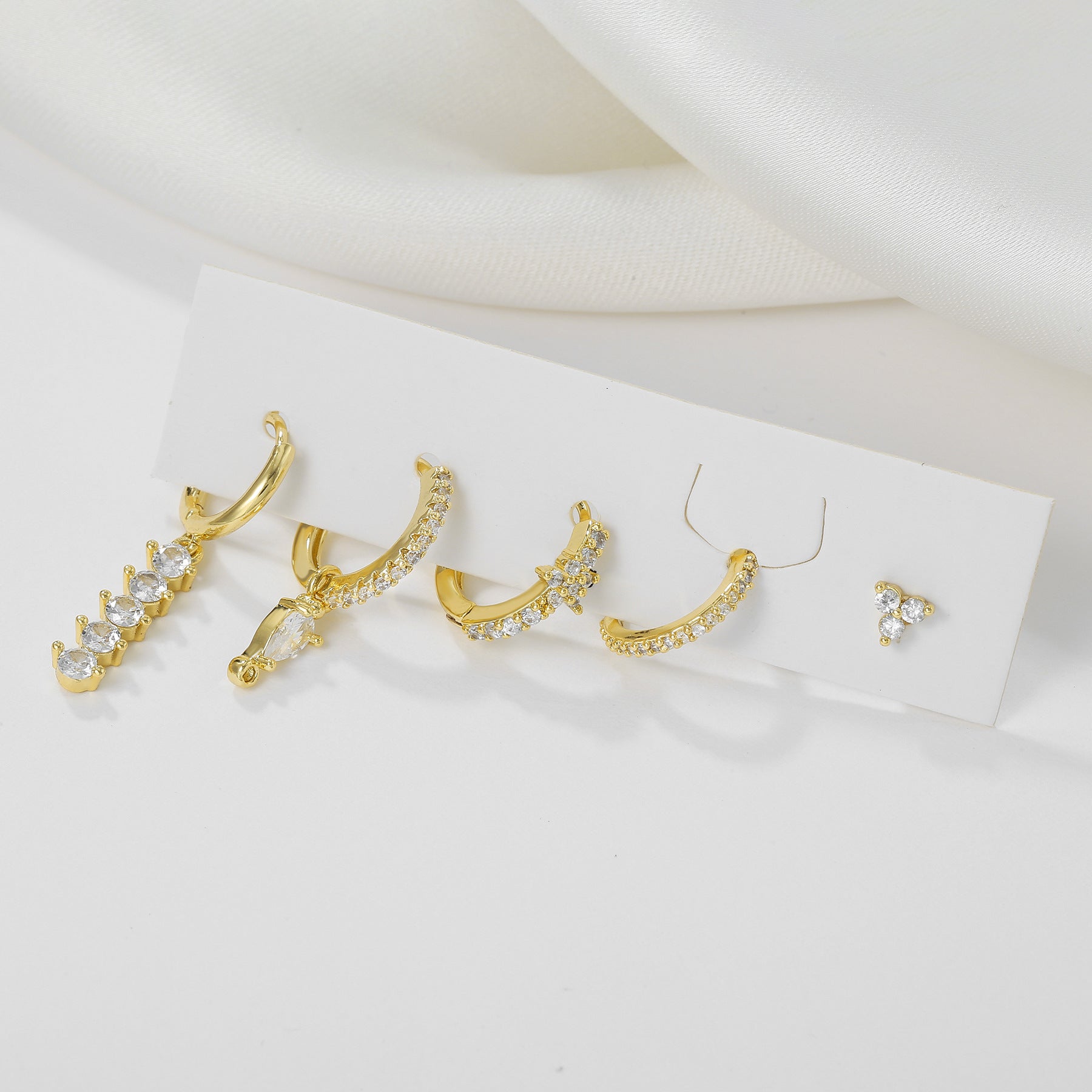 Gold earrings with clear stones on a white background