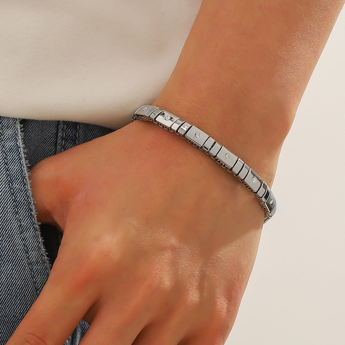 Silver bracelet on a wrist with a neutral background