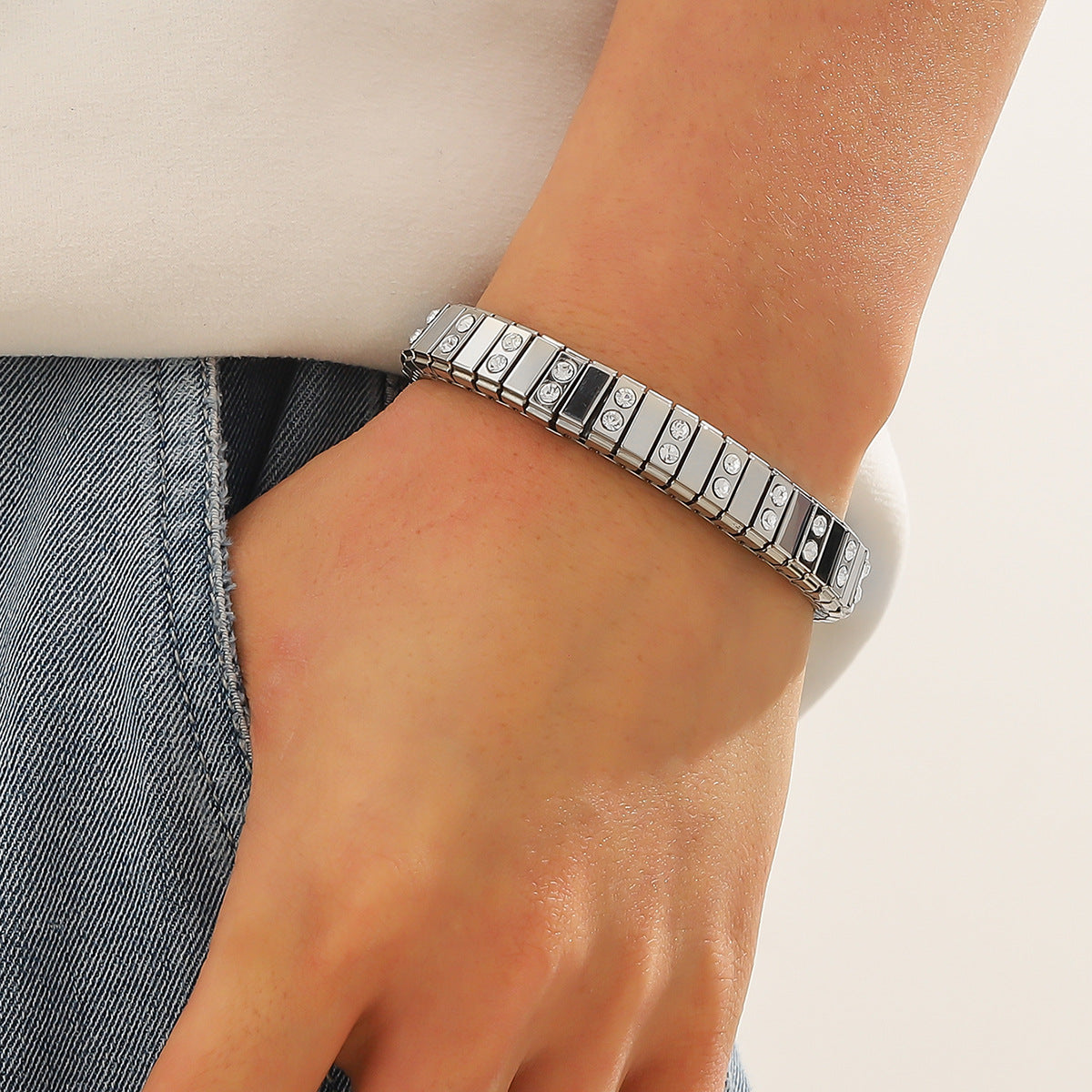 Silver bracelet on a wrist with a neutral background