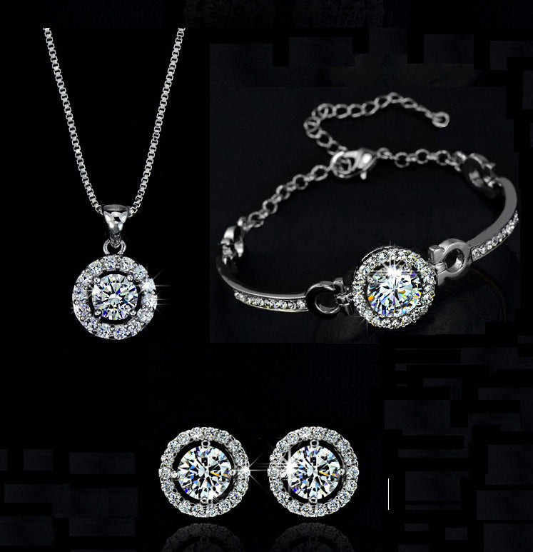 Silver jewelry set with necklace, bracelet, and earrings on a black background
