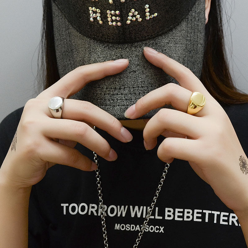 Close-up of hands wearing gold rings with a text overlay on a plain background