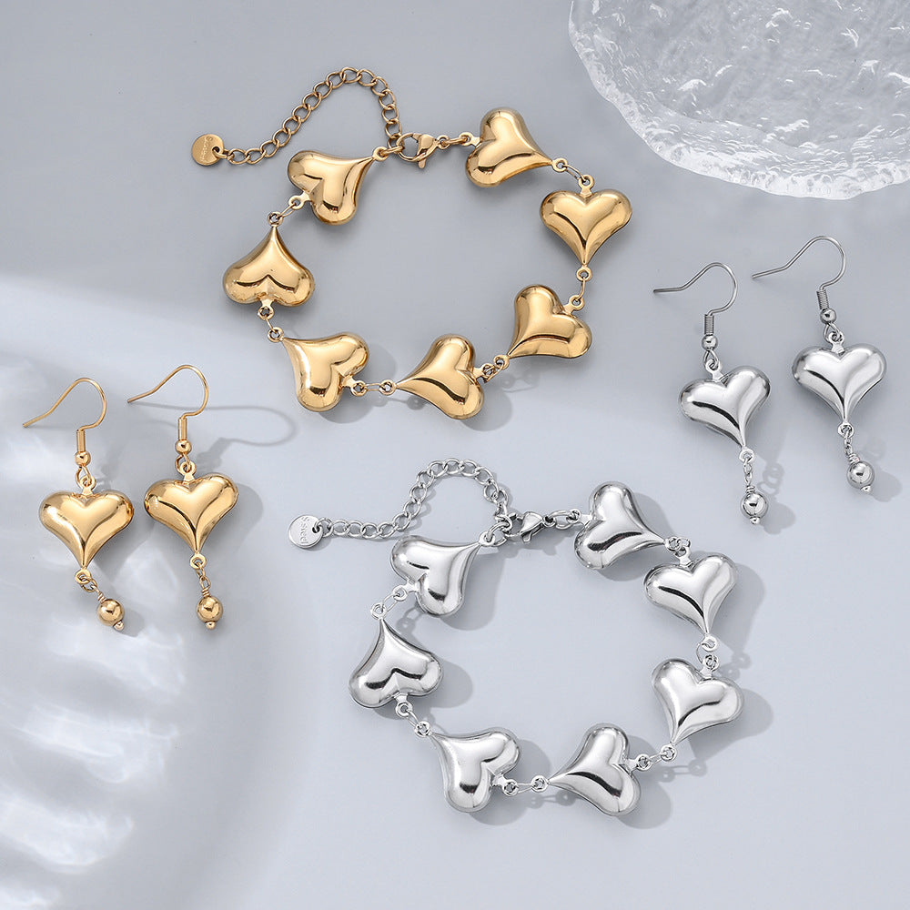 Gold and silver heart-shaped jewelry set on a light gray background