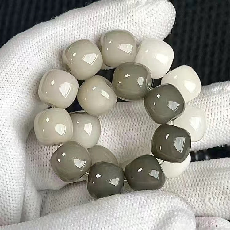 Beaded bracelet with gray and white beads on a textured surface