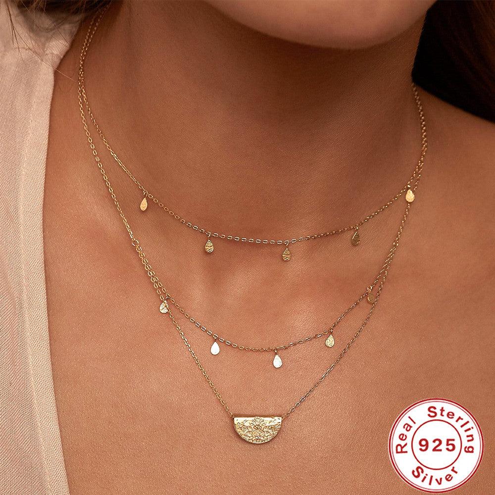 Gold necklace with a half-circle pendant on a person's neck, featuring a 'Real Sterling Silver 925' stamp.