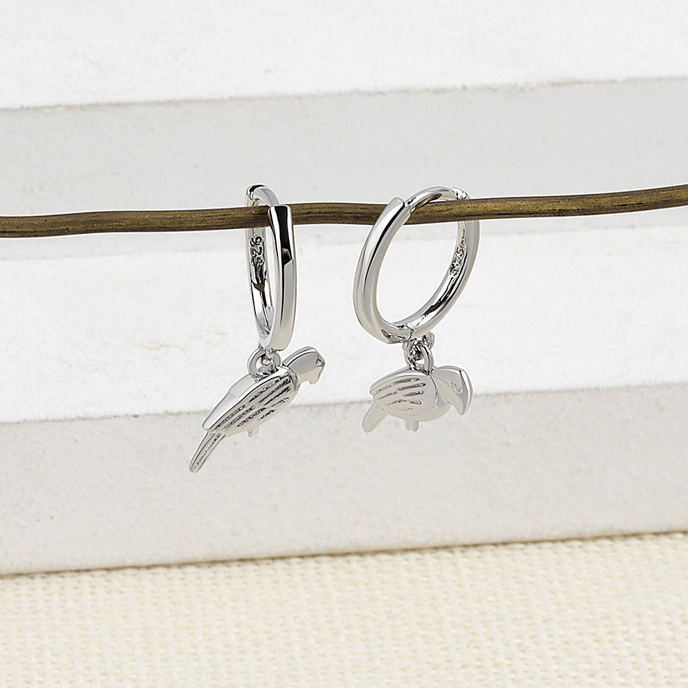 Silver hoop earrings with bird charms on a white background