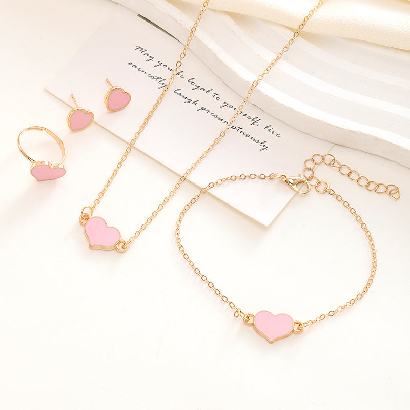 Jewelry set with pink heart charms on gold chains on a white background