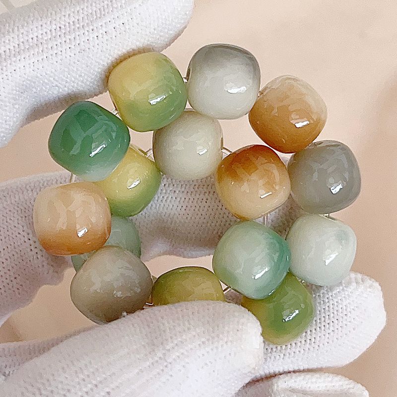 Multicolored beaded bracelet held by a gloved hand on a beige background