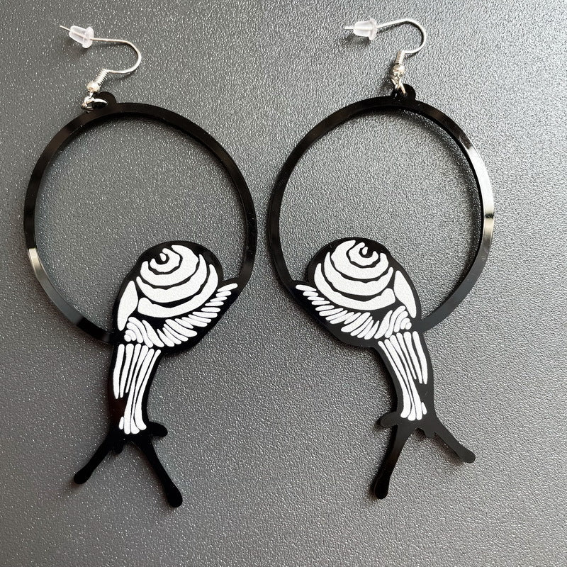 Black hoop earrings with white fish design on a gray background
